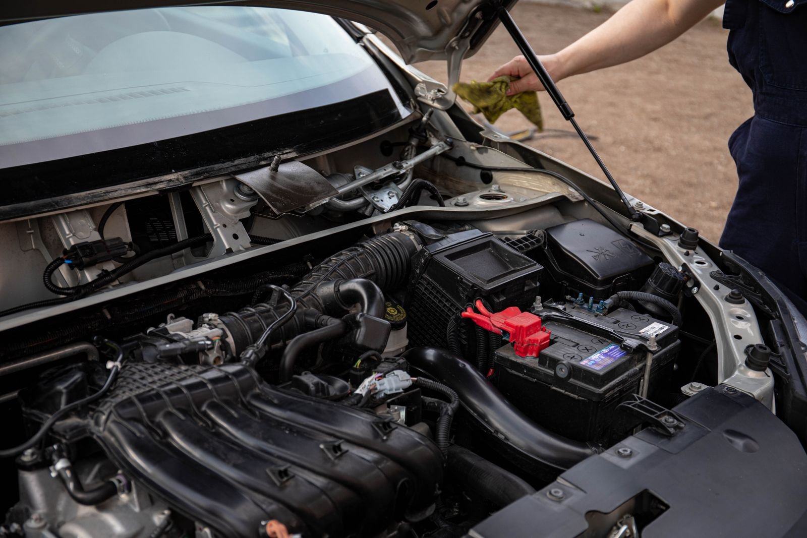 Car battery inspection and replacement under an open bonnet
